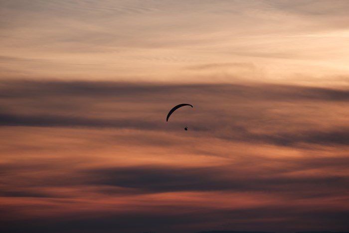 Paraglider flying in the sky at sunset