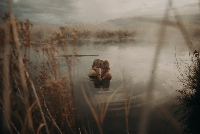 Two people kissing in a misty lake with reeds