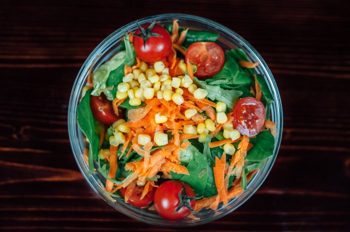 Healthy salad with tomatoes, corn, and carrots in a bowl