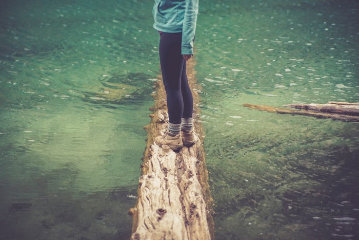 Woman walking on a log over water