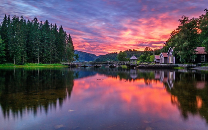 Sunset over a lake with houses and a bridge