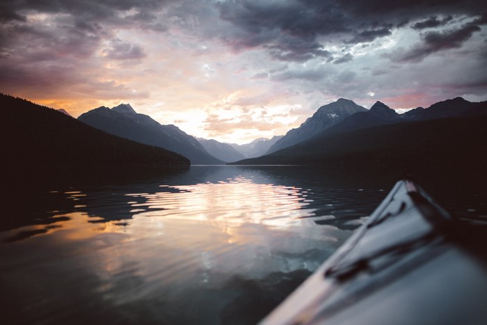 Kayaking on a lake at sunrise with mountains