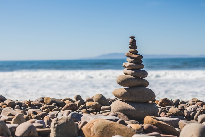 Stack of balanced stones on a beach with ocean waves