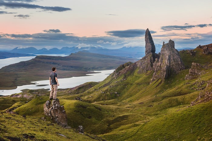 Man standing on rock overlooking Scottish landscape