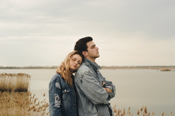 Couple leaning on each other by a lake