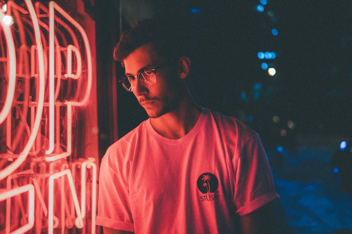 Man wearing glasses and t-shirt near neon lights