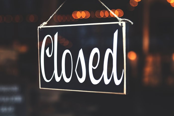 A black sign with the word "Closed" hangs in front of bokeh lights.