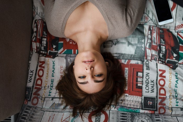 Woman lying on London-themed bedding with phone