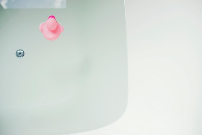 Pink rubber duck floating in a bathtub