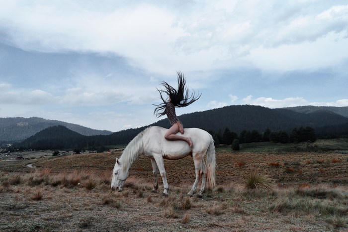 Woman riding a white horse in a mountainous landscape