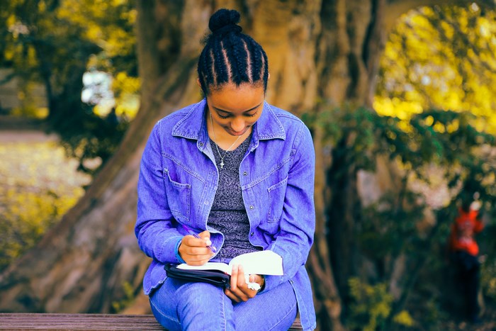 African American woman reading and writing in a park