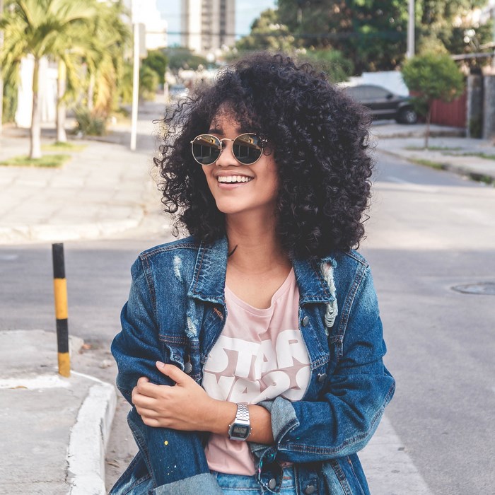 Woman with curly hair wearing a Star Wars shirt and jean jacket