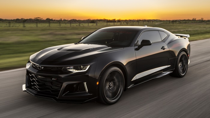 Black Chevrolet Camaro ZL1 driving on a road at sunset