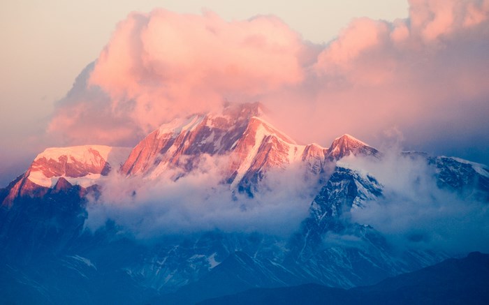 Pink clouds over snow-capped mountain range at sunset