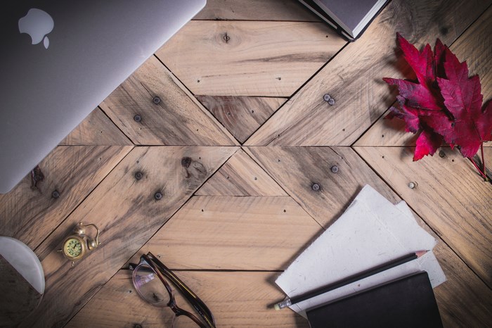 MacBook, glasses, and autumn leaf on a wooden table