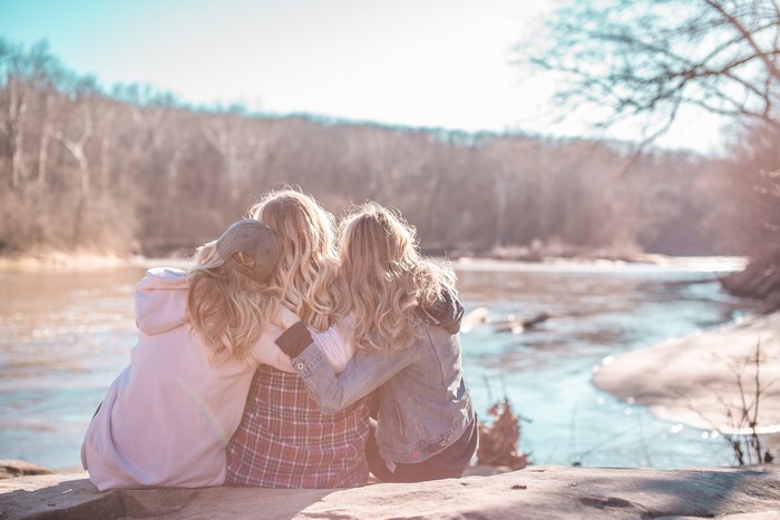 Three friends hugging by a river in the forest