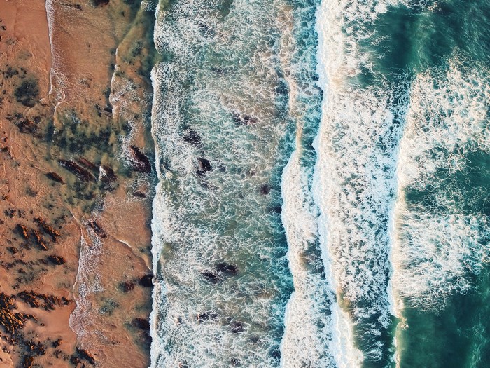 Aerial view of waves crashing on a sandy beach in Portugal