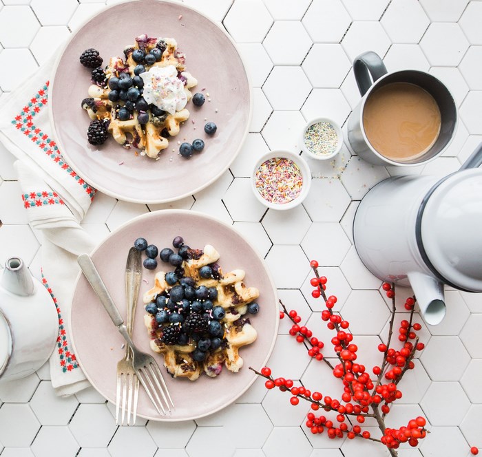 Two plates of waffles with blueberries and sprinkles
