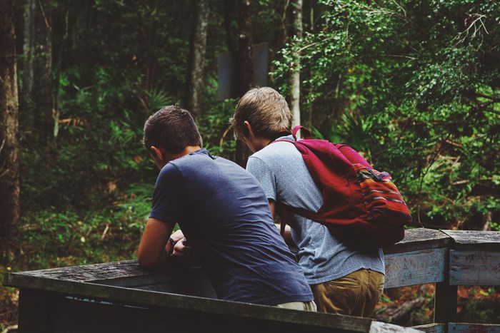 Two boys with backpacks in a forest