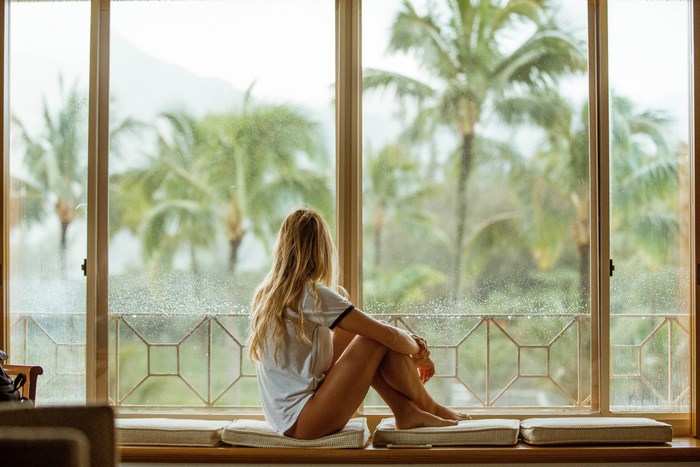 Woman Sitting by Window with Tropical Hawaii View