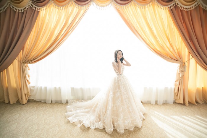 Elegant bride in lace wedding dress by bright window