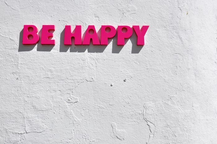Pink "BE HAPPY" sign on a white wall