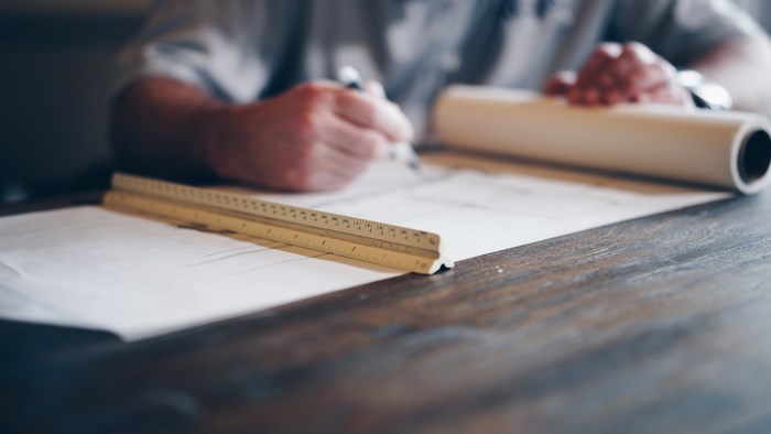 Architect working on blueprints with ruler and pen