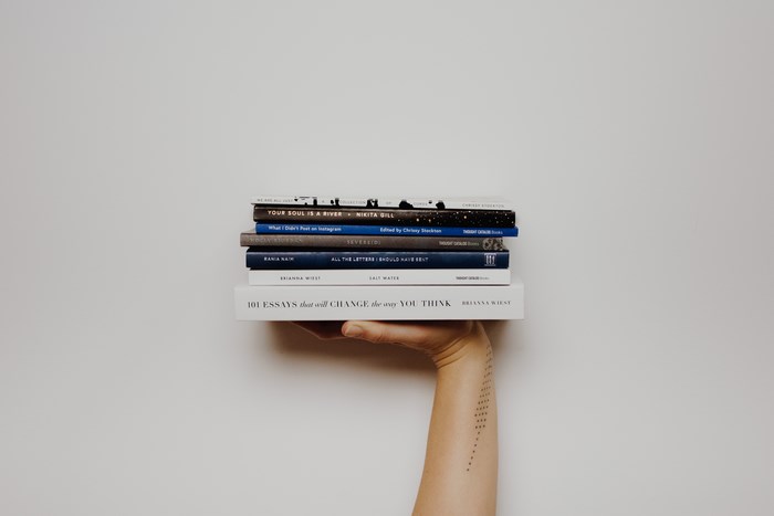Stack of Books Held by a Hand with Tattoo