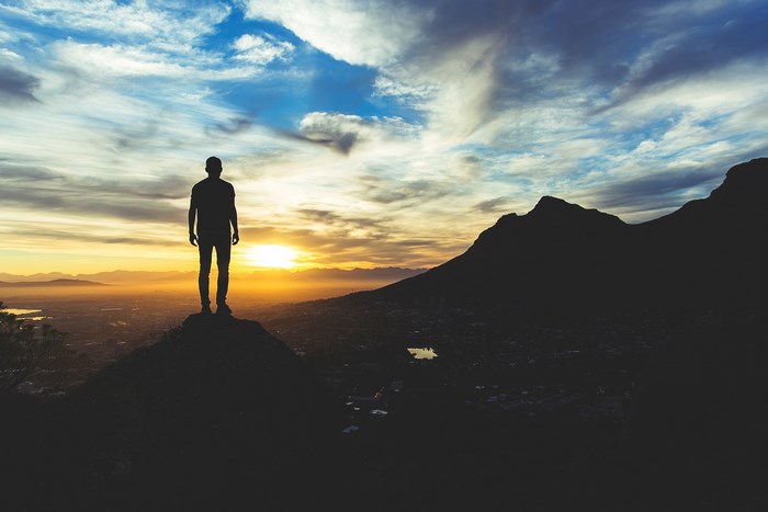 Man standing on a mountain overlooking Cape Town at sunrise
