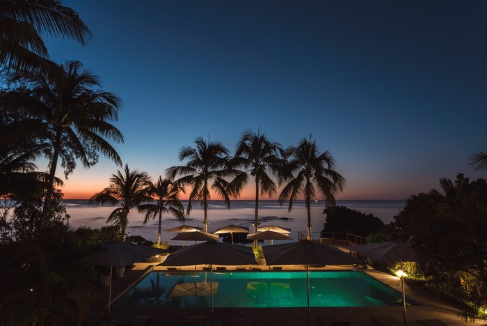 Palm trees and pool at dusk by the ocean