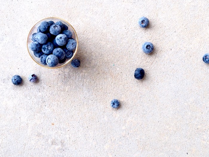 Blueberries in a glass bowl on a concrete surface