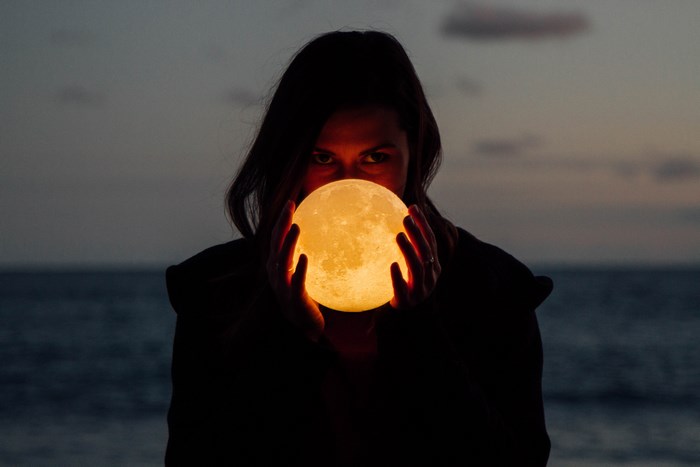 Woman holding a glowing moon lamp at dusk