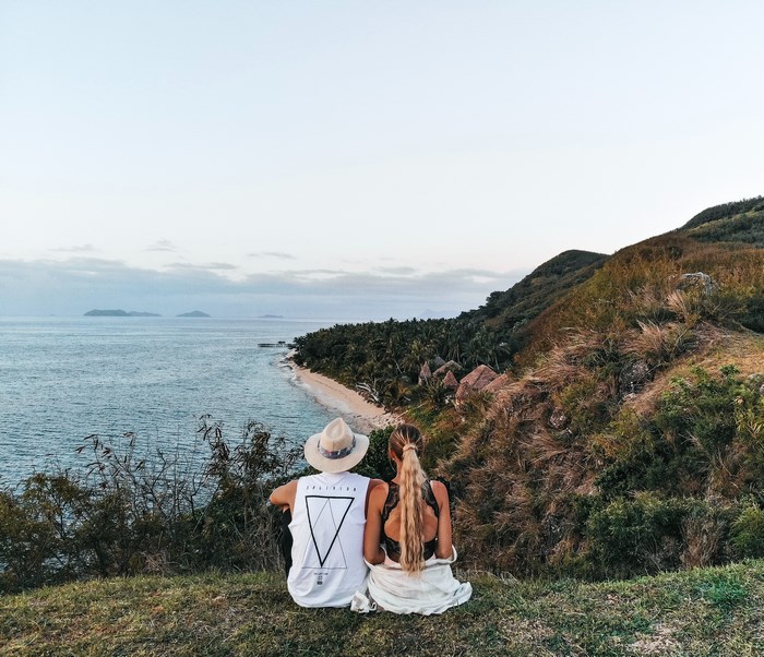 Couple sitting on a hill overlooking Fiji islands