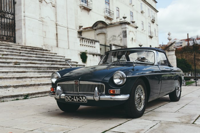 Dark blue classic MG convertible parked by stone stairs