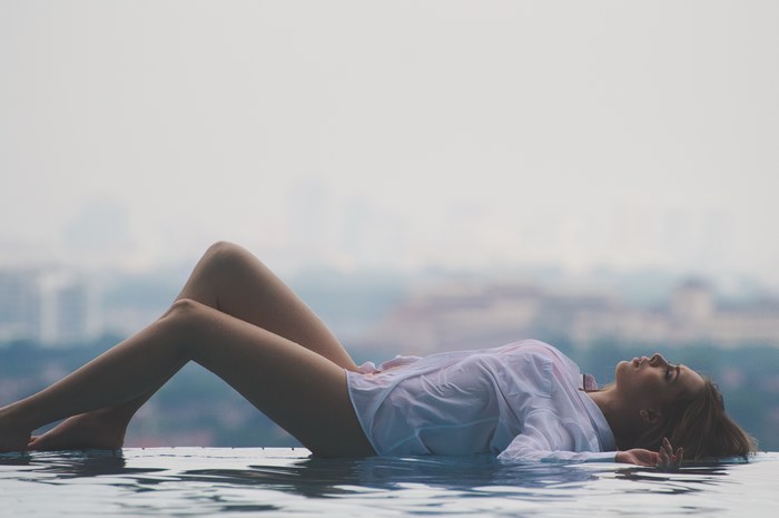Woman Relaxing on Rooftop Infinity Pool