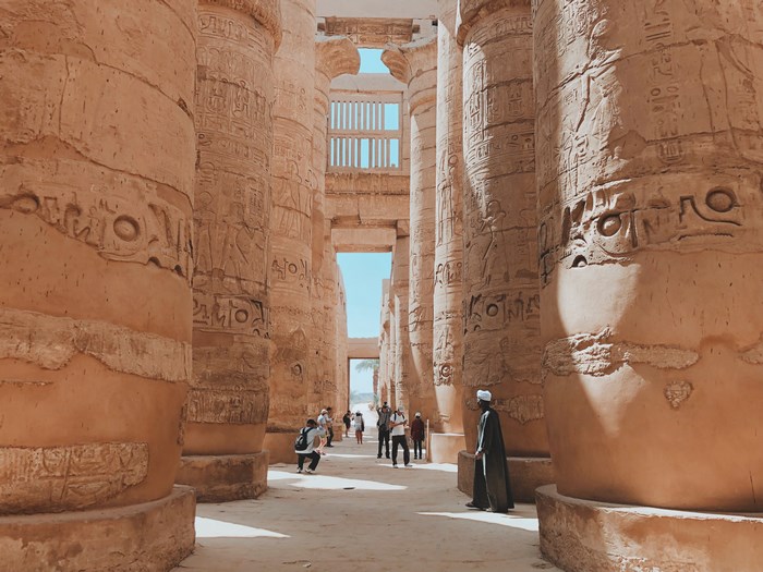 Tourists explore the ancient Egyptian temple with hieroglyphic pillars
