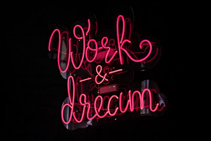 Pink neon sign that says "Work & Dream"