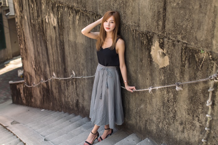 Asian Brunette Woman Wearing Black Top and Gray Skirt