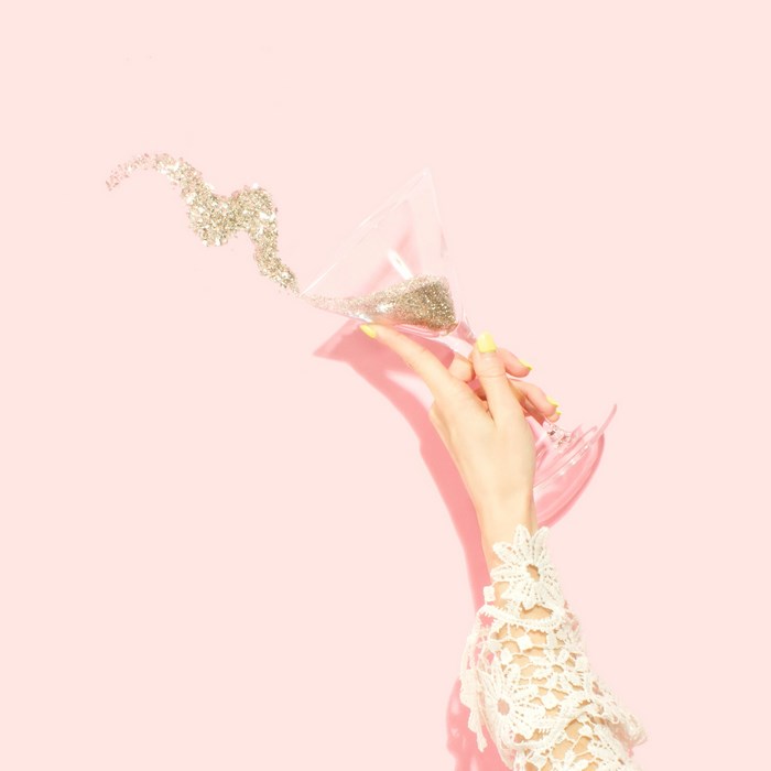 Hand holding martini glass with glitter spilling