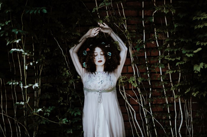 Woman with flowers in her hair in front of ivy wall