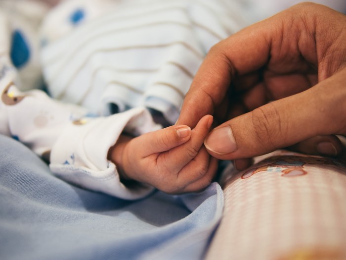 Parent holding a newborn baby's hand