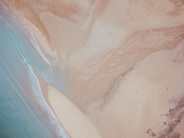 Aerial view of a beach with waves and sand patterns