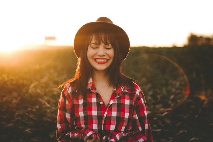 Woman in plaid shirt and hat at sunset