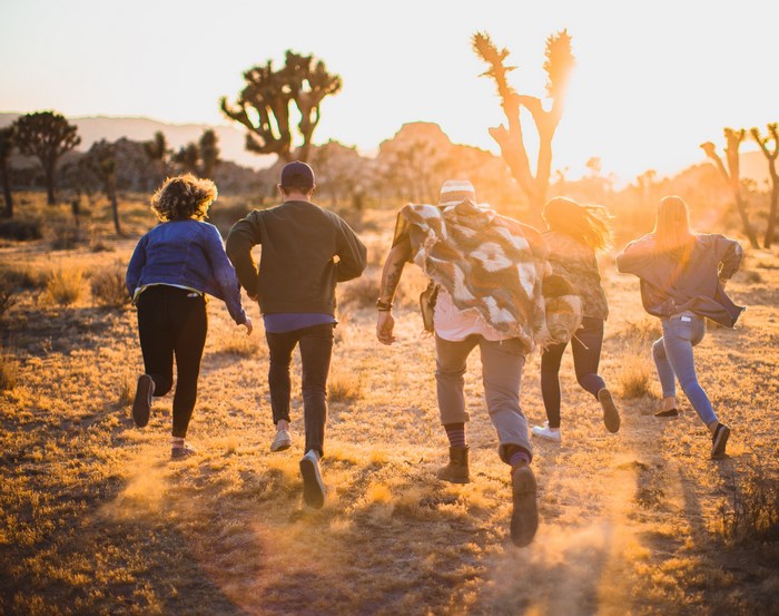 Group of friends running at sunset in a desert
