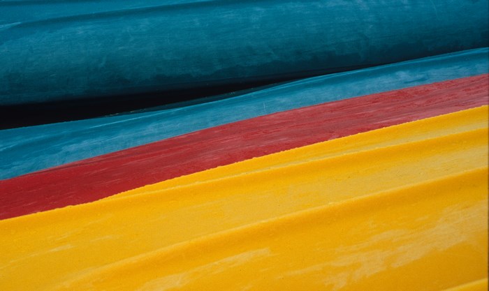 Three colorful kayaks in blue, red, and yellow