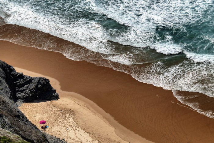 Beach with waves and a pink umbrella
