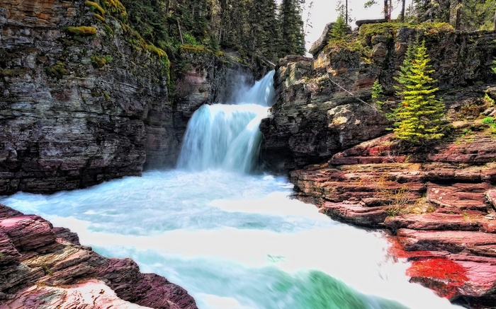 Waterfall cascading over red rocks in a forest
