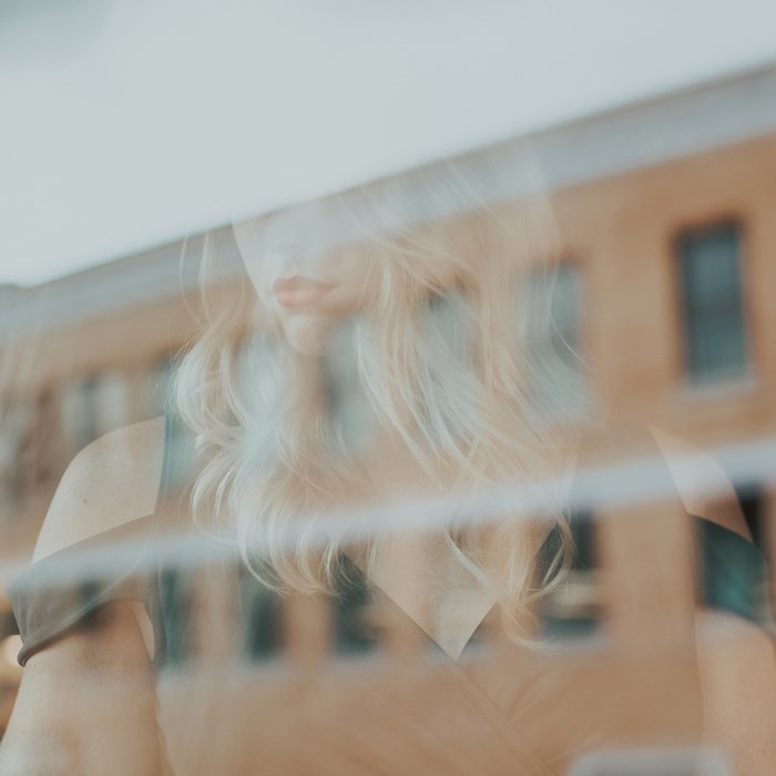Woman reflected in a window with a building in the background