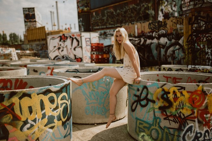 Blonde Woman Sitting on Graffiti-Covered Concrete