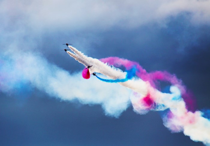 Four jets perform aerial maneuvers with colored smoke